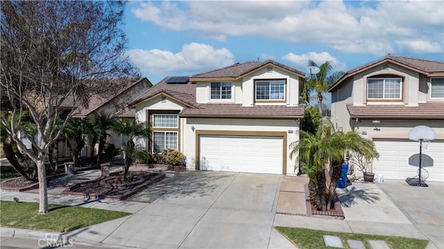 traditional home with a garage, a tile roof, driveway, roof mounted solar panels, and stucco siding