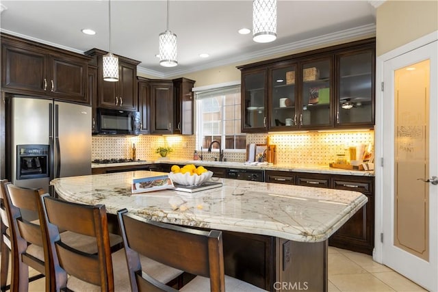 kitchen featuring light tile patterned floors, hanging light fixtures, dark brown cabinets, black appliances, and a kitchen bar