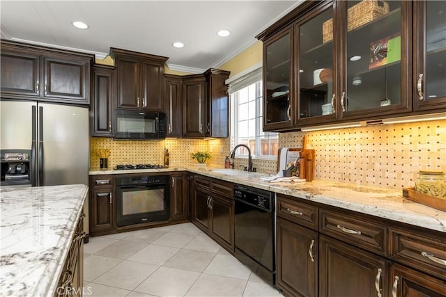 kitchen featuring light stone counters, crown molding, a sink, dark brown cabinets, and black appliances