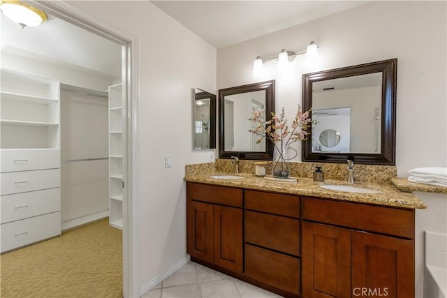 bathroom featuring a sink, a spacious closet, baseboards, and double vanity