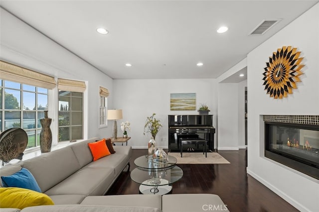 living area with baseboards, visible vents, a glass covered fireplace, dark wood-style flooring, and recessed lighting