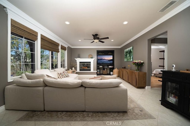 living room featuring recessed lighting, visible vents, crown molding, and a glass covered fireplace