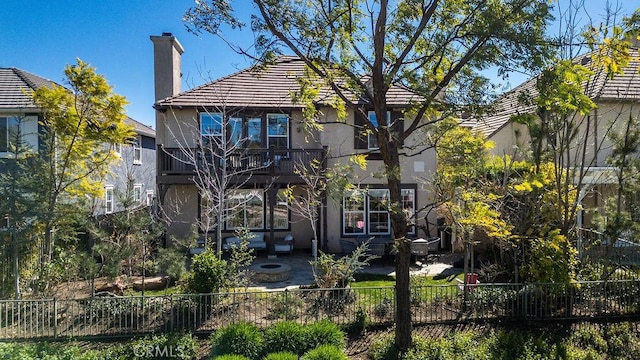 rear view of property with a patio, a chimney, fence, and stucco siding