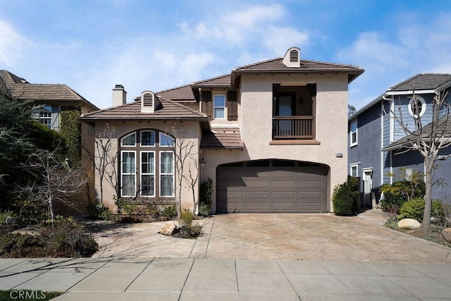 view of front of property featuring a balcony, a garage, a tile roof, concrete driveway, and stucco siding