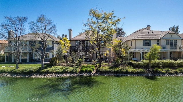 rear view of property featuring a water view and a chimney