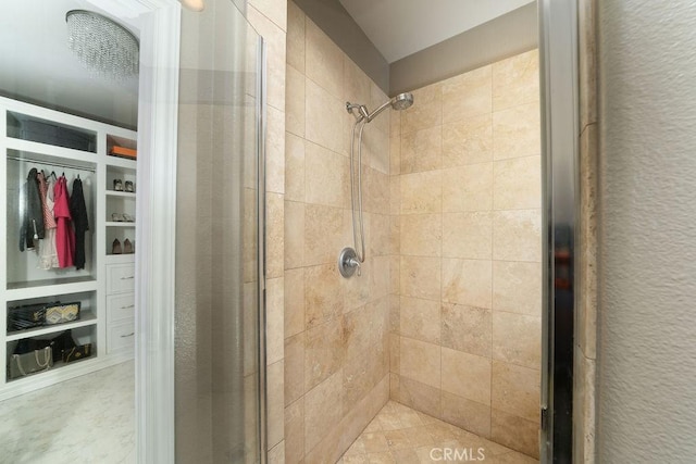 bathroom with a textured wall, a spacious closet, and a stall shower