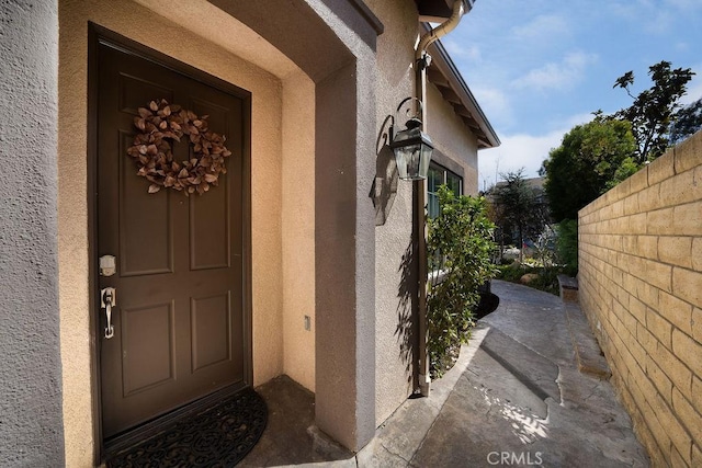 entrance to property with fence and stucco siding