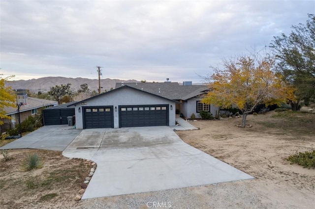 ranch-style home with a garage, concrete driveway, a mountain view, and stucco siding