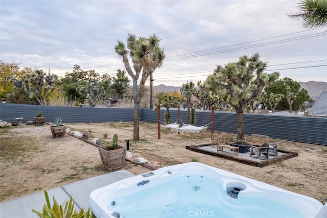 view of yard featuring an outdoor fire pit, fence, and a hot tub