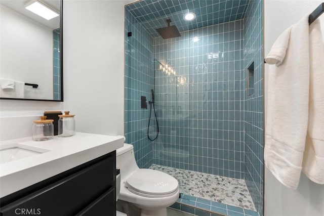 full bathroom featuring toilet, a tile shower, and vanity