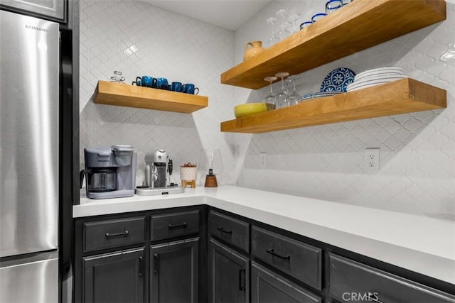 kitchen featuring tasteful backsplash, open shelves, light countertops, and freestanding refrigerator