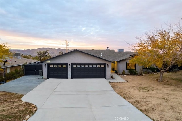 view of front facade featuring a garage, a mountain view, driveway, and stucco siding