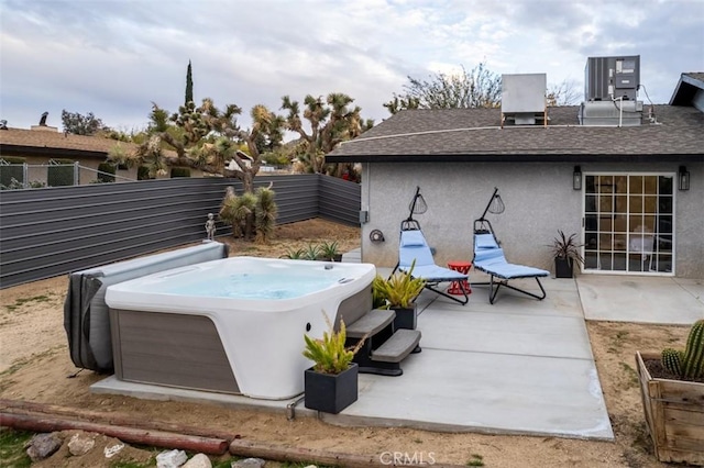 view of patio with fence, a hot tub, and central AC unit