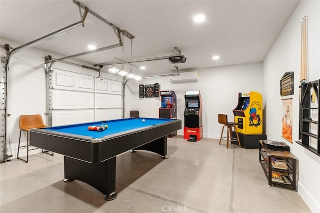 game room featuring a garage, a wall unit AC, finished concrete flooring, and baseboards