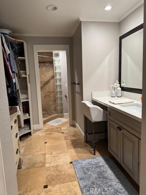 bathroom featuring a walk in closet, a tile shower, and crown molding