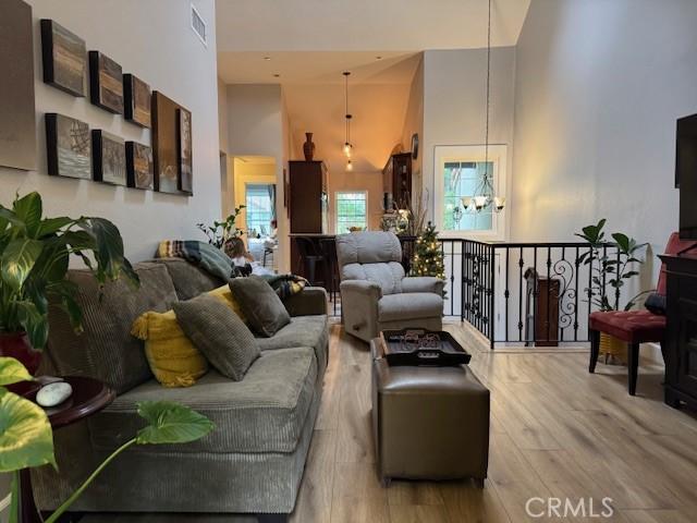 living room featuring a high ceiling, light wood-style floors, and visible vents