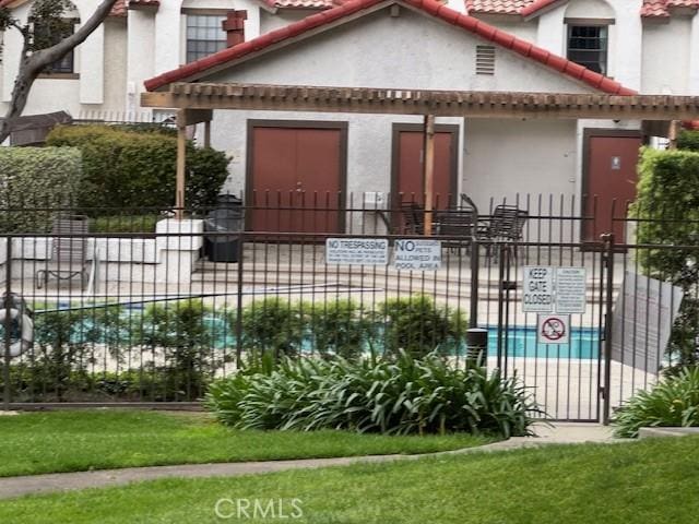 rear view of property featuring stucco siding, a tile roof, and fence