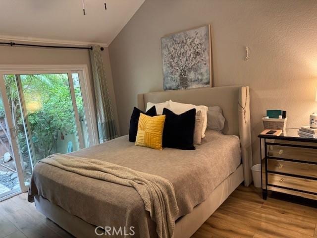 bedroom featuring lofted ceiling, wood finished floors, and access to exterior