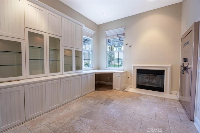 interior space featuring a glass covered fireplace and built in study area