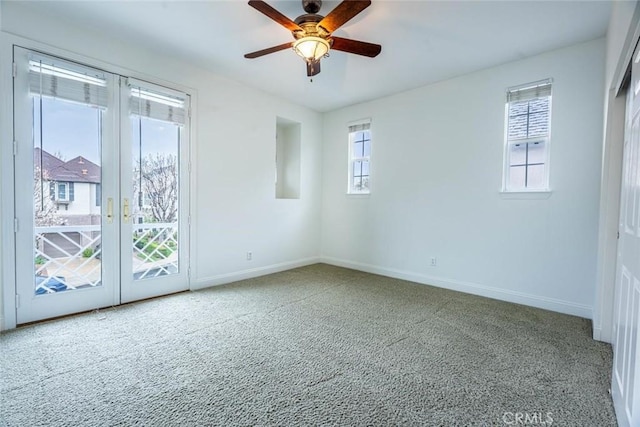 carpeted spare room featuring ceiling fan, baseboards, and french doors