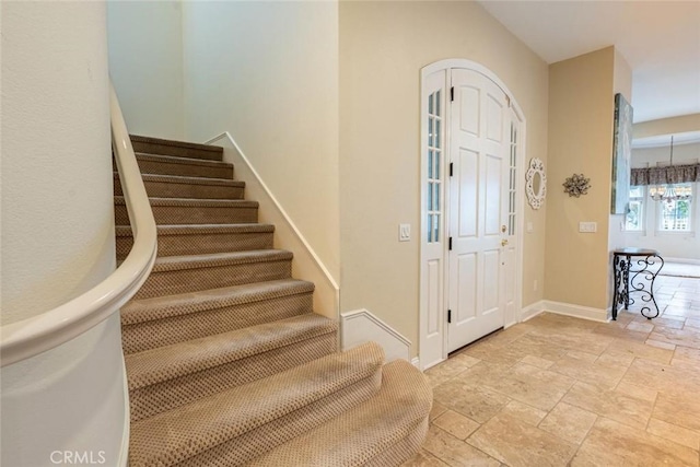 entrance foyer with a chandelier, stone tile flooring, baseboards, and stairs