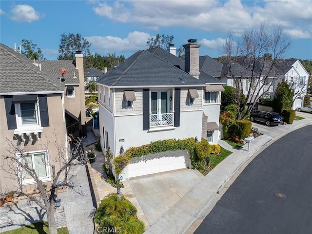 view of front of house featuring a garage, a shingled roof, concrete driveway, stucco siding, and a chimney