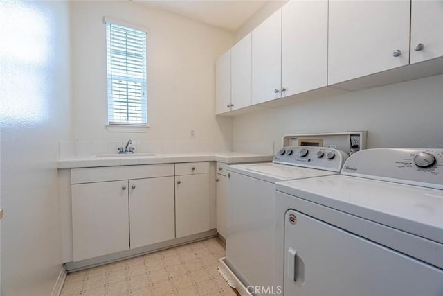 clothes washing area with cabinet space, a sink, light floors, and separate washer and dryer