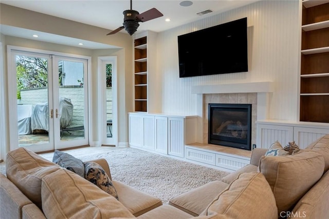 living room featuring visible vents, built in features, baseboards, french doors, and a fireplace