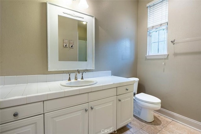 bathroom with vanity, toilet, and baseboards