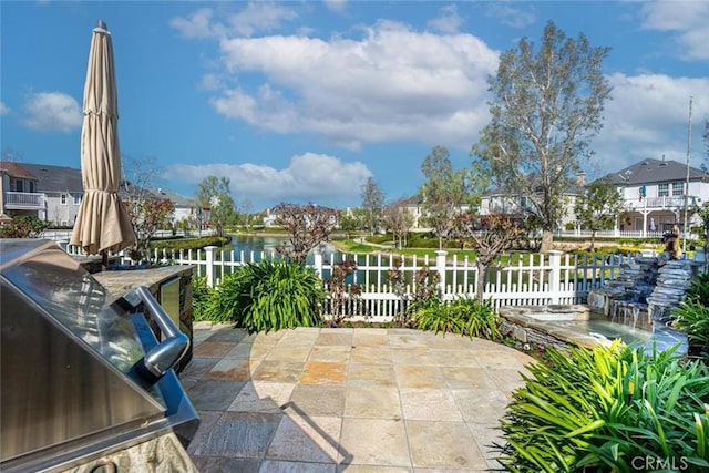 view of patio with a water view and fence