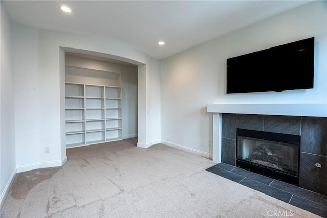 unfurnished living room featuring carpet floors, recessed lighting, a tile fireplace, and baseboards