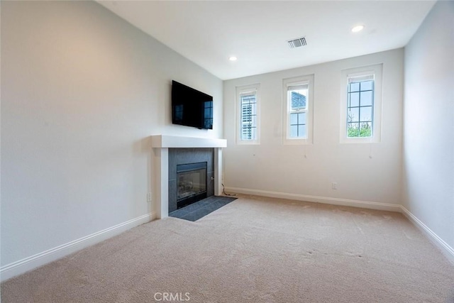 unfurnished living room featuring carpet floors, a tile fireplace, visible vents, and baseboards