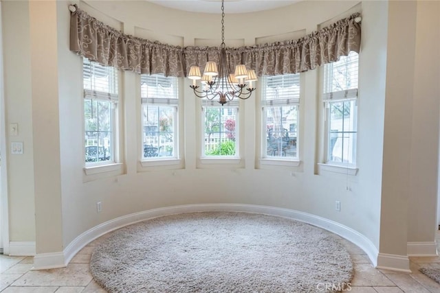 tiled dining room with a healthy amount of sunlight, baseboards, and a notable chandelier