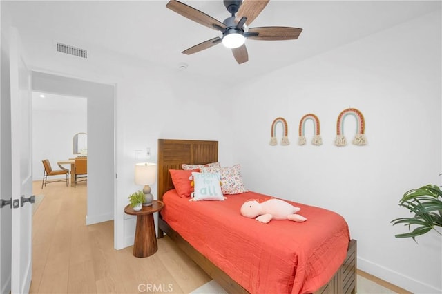 bedroom with a ceiling fan, visible vents, light wood-style flooring, and baseboards