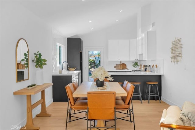 dining room with high vaulted ceiling, recessed lighting, light wood-style flooring, and baseboards