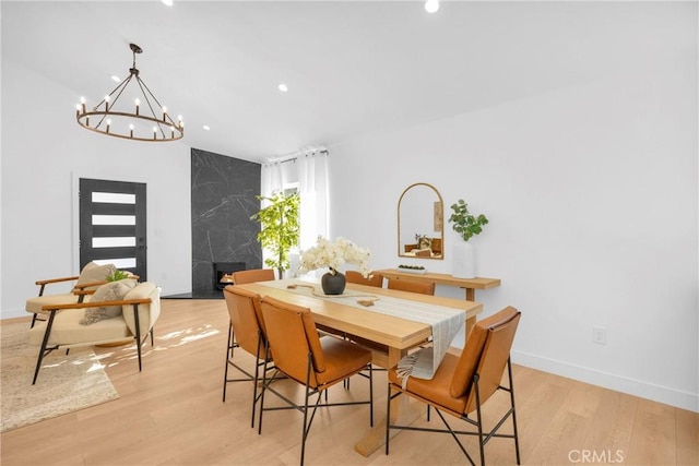 dining room featuring a fireplace, lofted ceiling, recessed lighting, light wood-type flooring, and baseboards