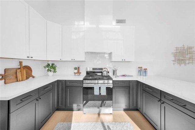 kitchen with light countertops, visible vents, stainless steel gas range oven, and white cabinetry