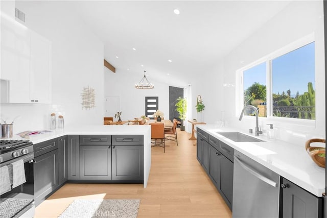 kitchen with visible vents, black gas range oven, stainless steel dishwasher, a sink, and a chandelier