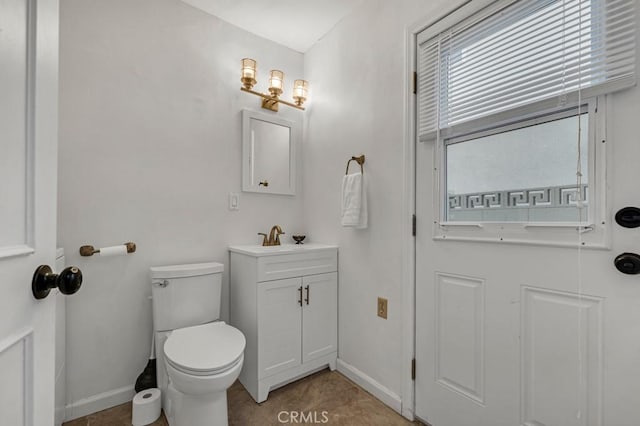 bathroom featuring baseboards, vanity, and toilet
