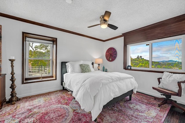 bedroom featuring crown molding, wood finished floors, baseboards, a textured ceiling, and a ceiling fan
