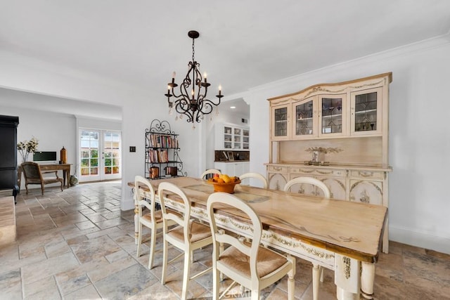 dining room featuring baseboards, stone tile floors, a chandelier, and ornamental molding