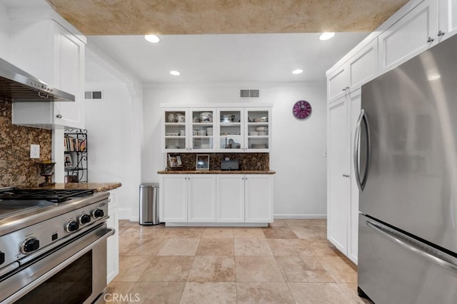 kitchen with wall chimney range hood, backsplash, visible vents, white cabinets, and stainless steel appliances