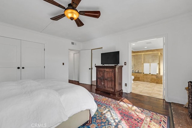 bedroom featuring crown molding, multiple closets, hardwood / wood-style floors, and visible vents
