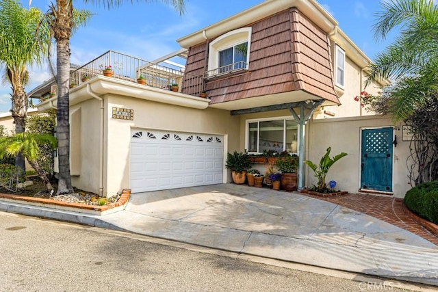 traditional-style home with mansard roof, stucco siding, driveway, and a balcony