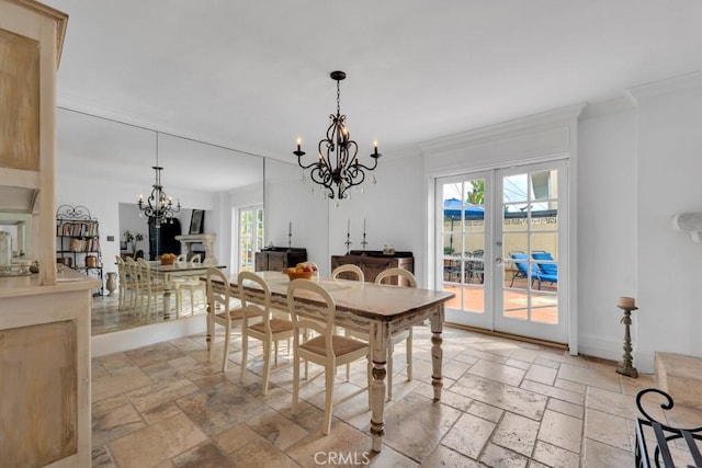 dining space featuring stone tile floors, crown molding, a notable chandelier, and a healthy amount of sunlight
