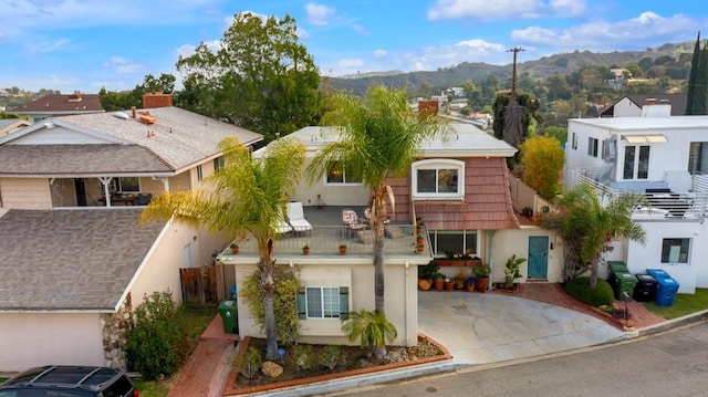view of front facade with stucco siding, a mountain view, a chimney, and concrete driveway