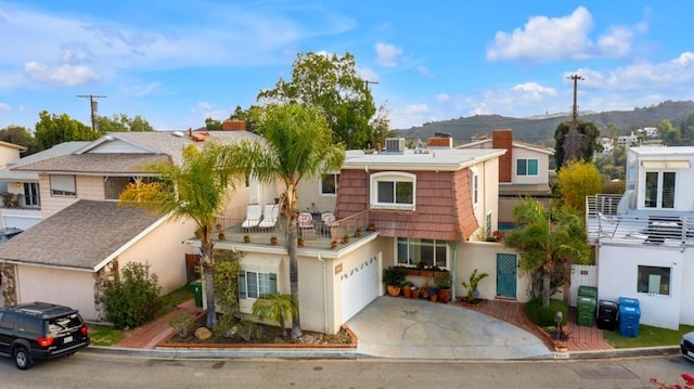 view of front of property featuring a residential view, a garage, stucco siding, a balcony, and driveway