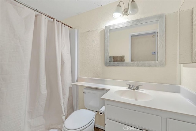 bathroom with a textured wall, a shower with shower curtain, vanity, and toilet