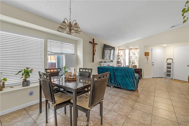 dining area with light tile patterned floors, a textured ceiling, a chandelier, baseboards, and vaulted ceiling