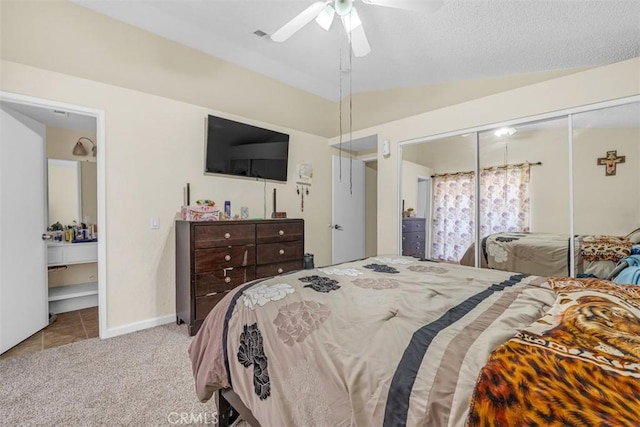 carpeted bedroom with ceiling fan, lofted ceiling, tile patterned flooring, baseboards, and ensuite bath